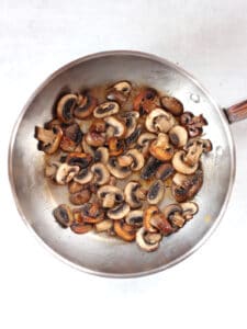 Browned mushrooms in a silver skillet.