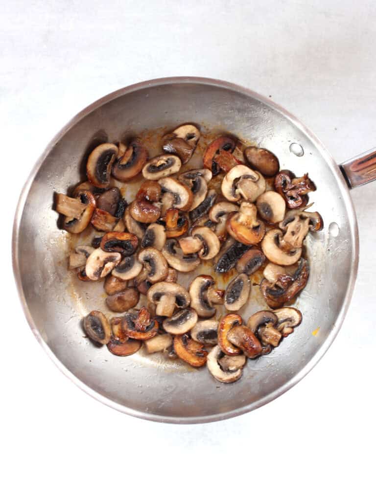 Browned mushrooms in a silver skillet.