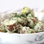 Red potato salad tossed in a creamy herb dressing served in a bowl.
