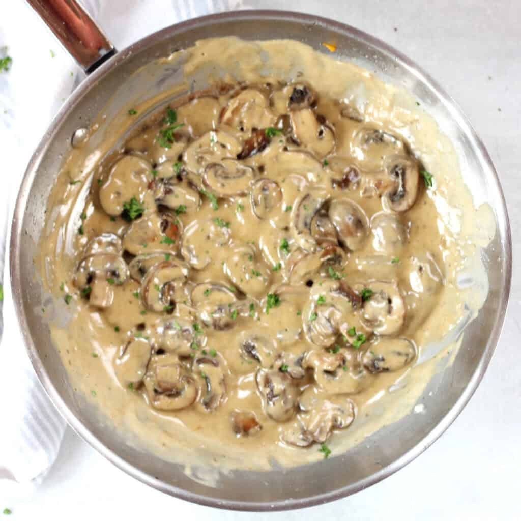Blue cheese mushrooms in a silver skillet garnished with fresh parsley.