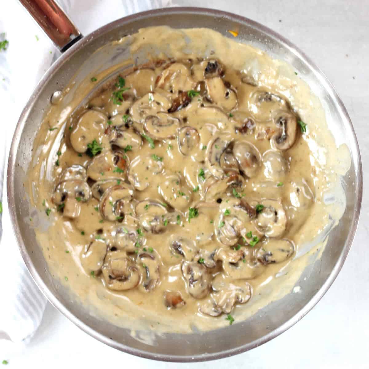 Blue cheese mushrooms in a silver skillet garnished with fresh parsley.