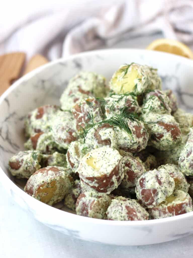 Baby red potatoes in creamy cottage cheese salad dressing, garnished with fresh dill.