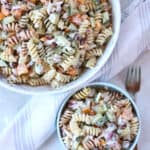 A large bowl of cottage cheese pasta salad, with some served into a smaller blue bowl.