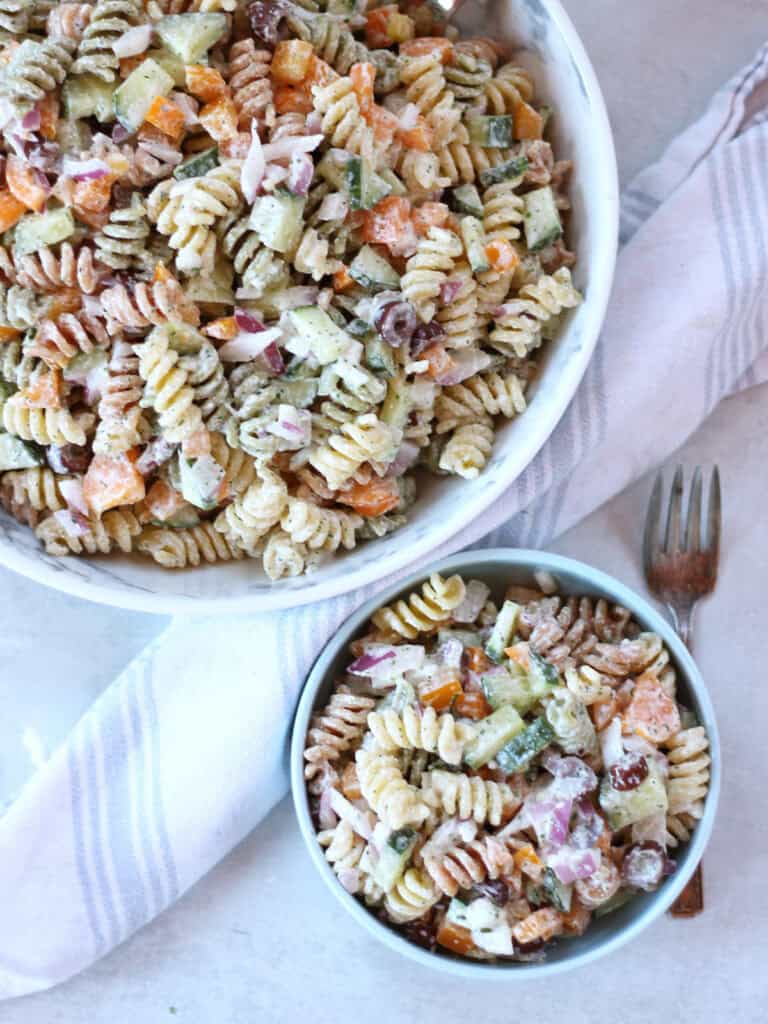 A large bowl of cottage cheese pasta salad, with some served into a smaller blue bowl.