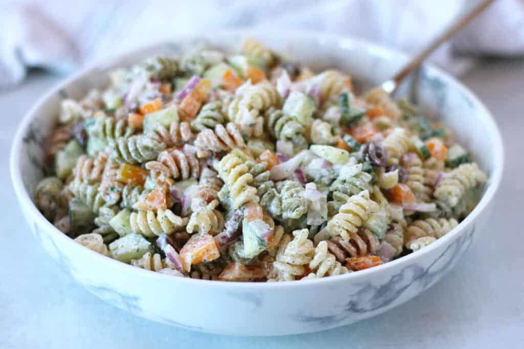 Pasta salad with chopped bell peppers, cucumber and red onion, served in a bowl.