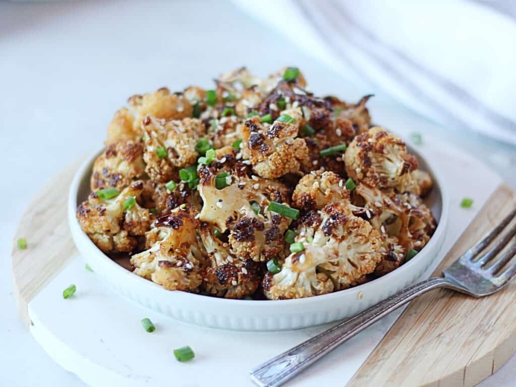 Roasted cauliflower in a honey garlic sauce served in s small bowl.