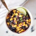 Overhead shot of a bowl of blueberry salsa with a lime slice.