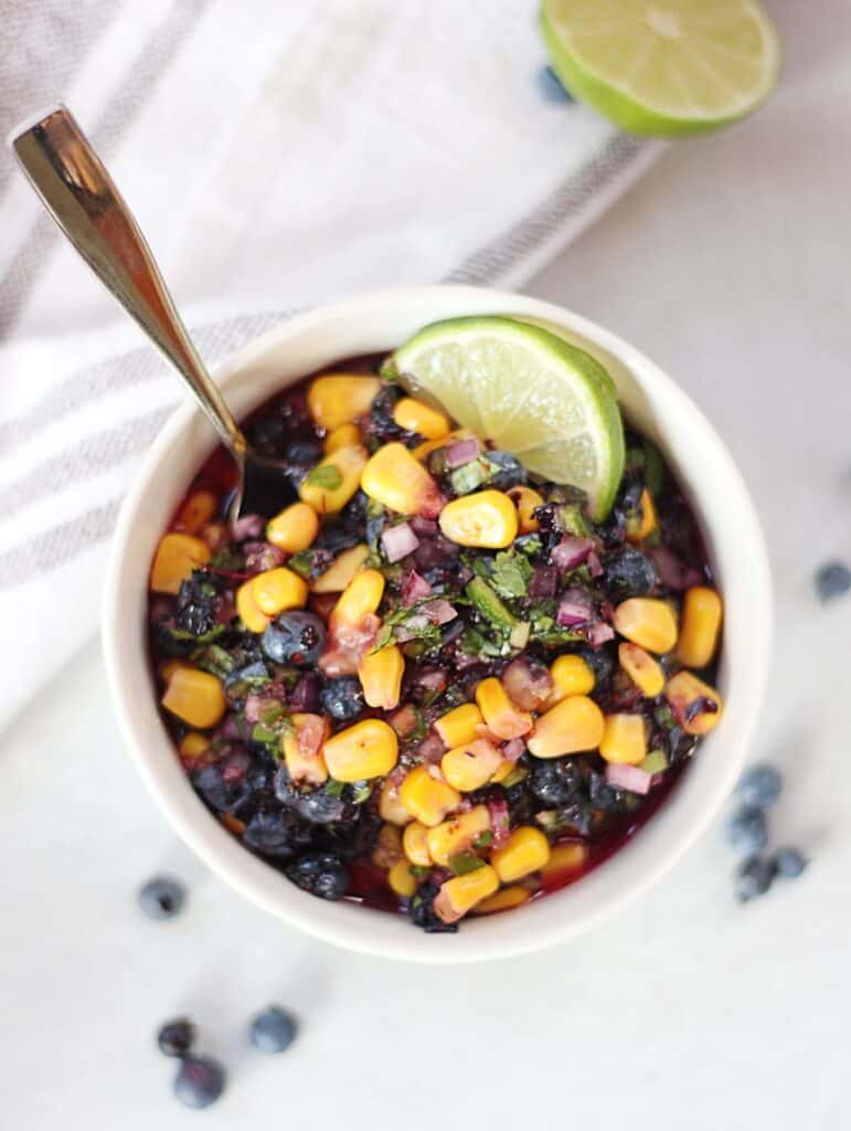 Overhead shot of a bowl of blueberry salsa with a lime slice.
