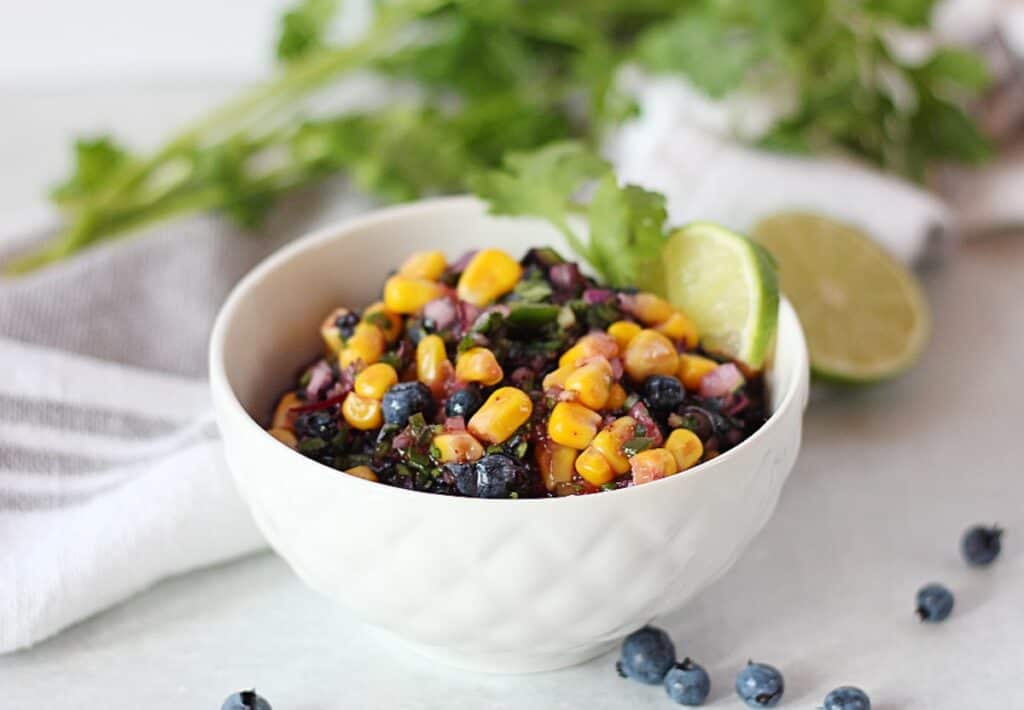 Fresh blueberry and corn salsa in a white bowl with garnish.
