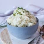 Cottage cheese mashed potato served in a blue bowl garnished with chives