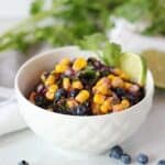 Corn salsa with fresh blueberries in a white bowl.