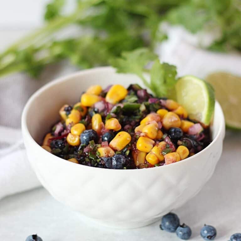 Corn salsa with fresh blueberries in a white bowl.