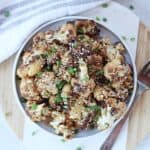 Seasoned roasted cauliflower served on a plate with a fork.