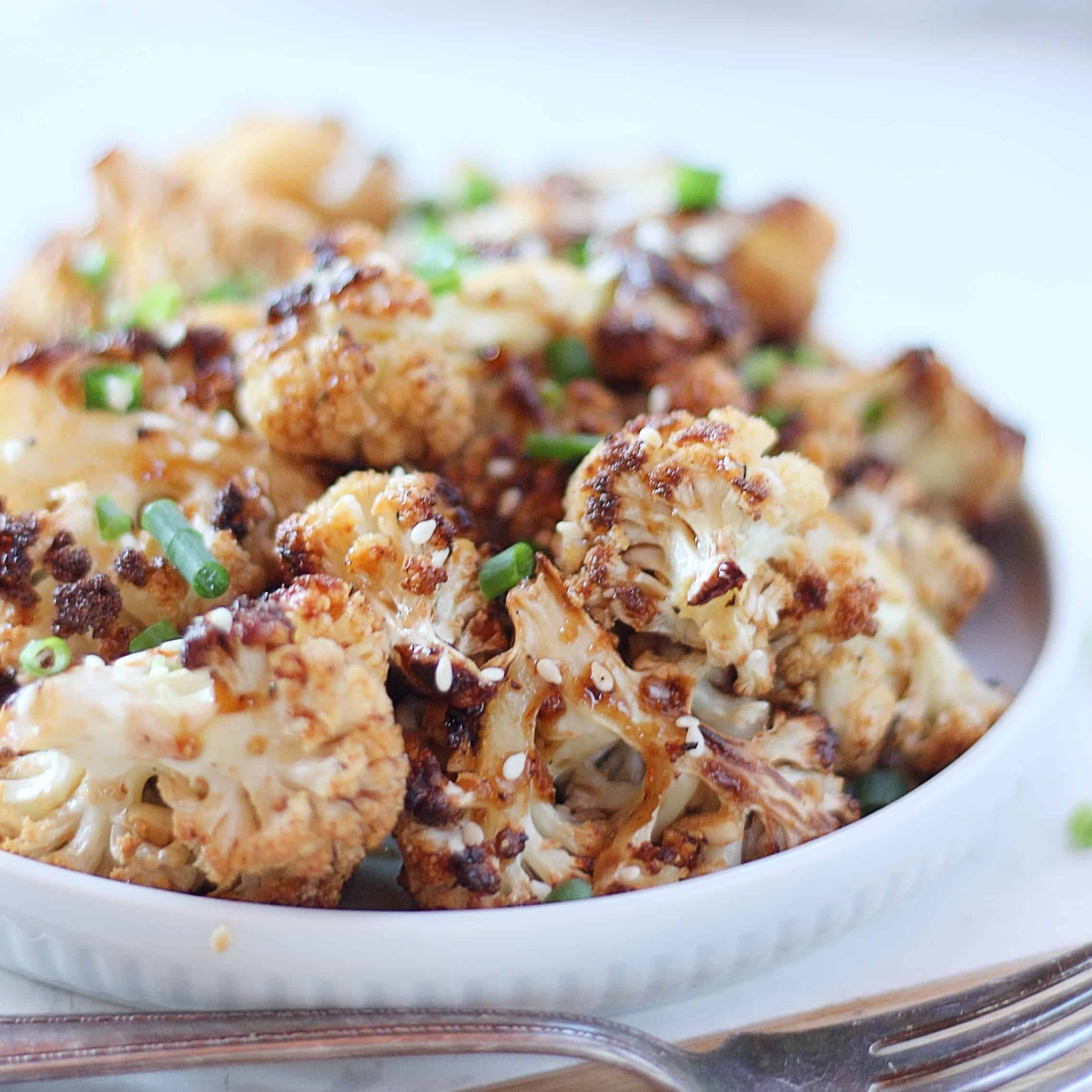 Honey garlic roasted cauliflower garnished with chives and sesame seeds.