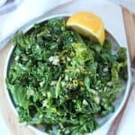 Garlic butter kale served on a small plate with a lemon slice.