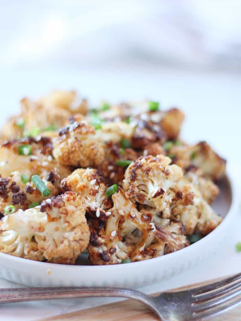 Honey garlic cauliflower garnished with fresh chives and sesame seeds.