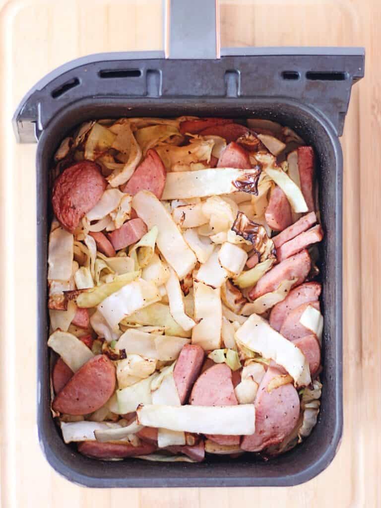 Kielbasa sausage and cabbage cooked in an air fryer basket.