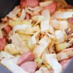 Kielbasa and cabbage in an air fryer basket.