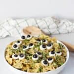 Halloween pasta salad served in a bowl with wooden serving spoons.